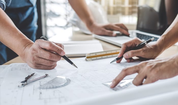 Men drawing blueprints on a jobsite